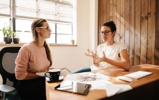 Why You Need Digital Marketing for Your Brand image of two women discussing marketing in an office setting