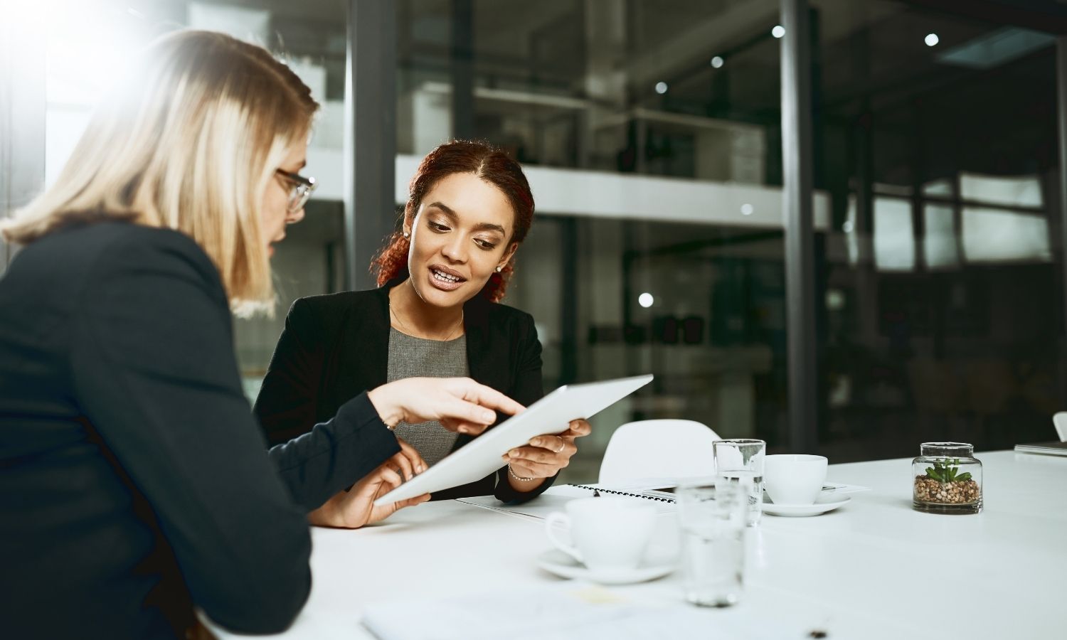 Five Tips to Attract Top Talent image of Two creative women sitting at an office table looking over paperwork. Creative Staffing Blog