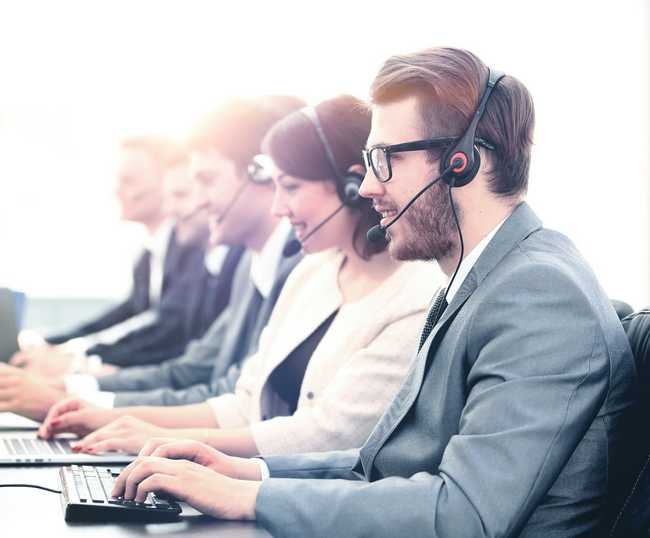 Image of Customer Service Call Center staff at work. Five people seen on the phone.