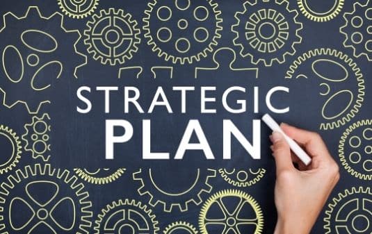 Person writing "Strategic Plan" on a chalkboard.