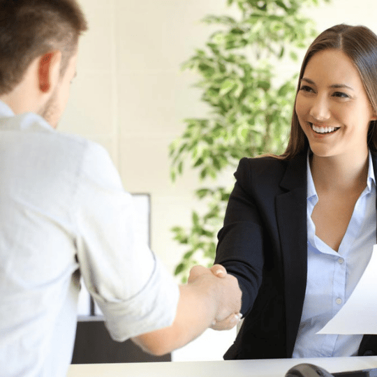 How to Stand Out to Human Resources image of male job applicant shaking hands with female interviewer